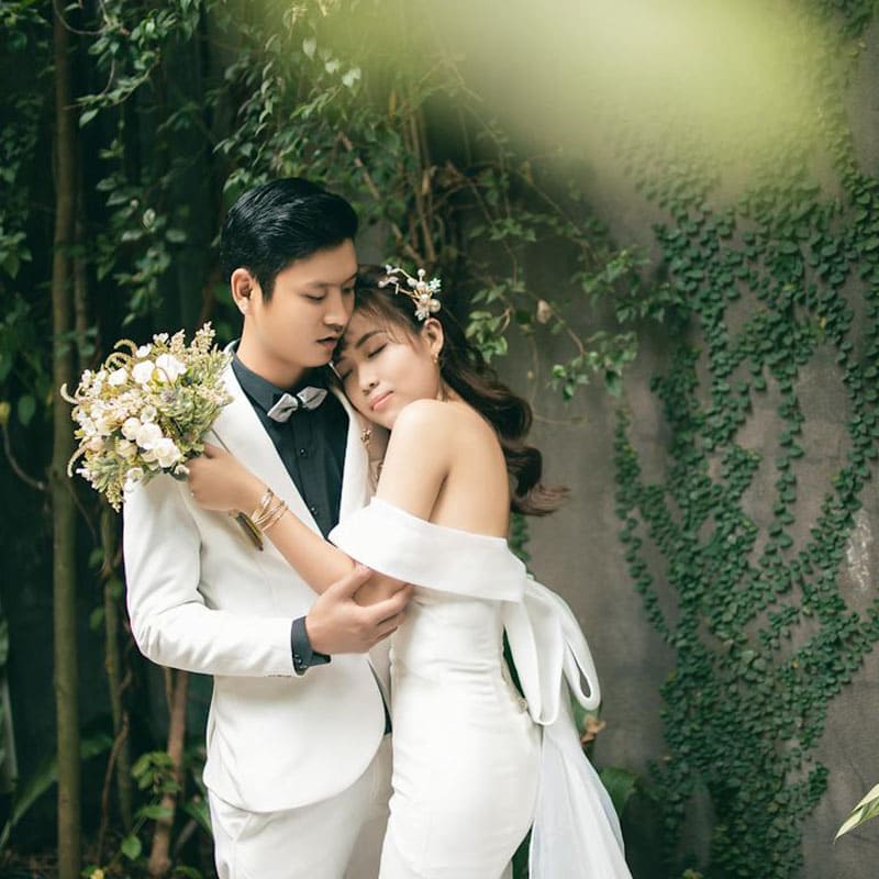 couple taking vintage photo with greens around